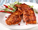Dwa soczyste plastry boczku na grilla, przyprawione ziołami i podane z papryczkami chili.
