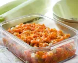 Pyszny bigos z cukinii w szklanym naczyniu, obok świeże cukinie i miseczki.