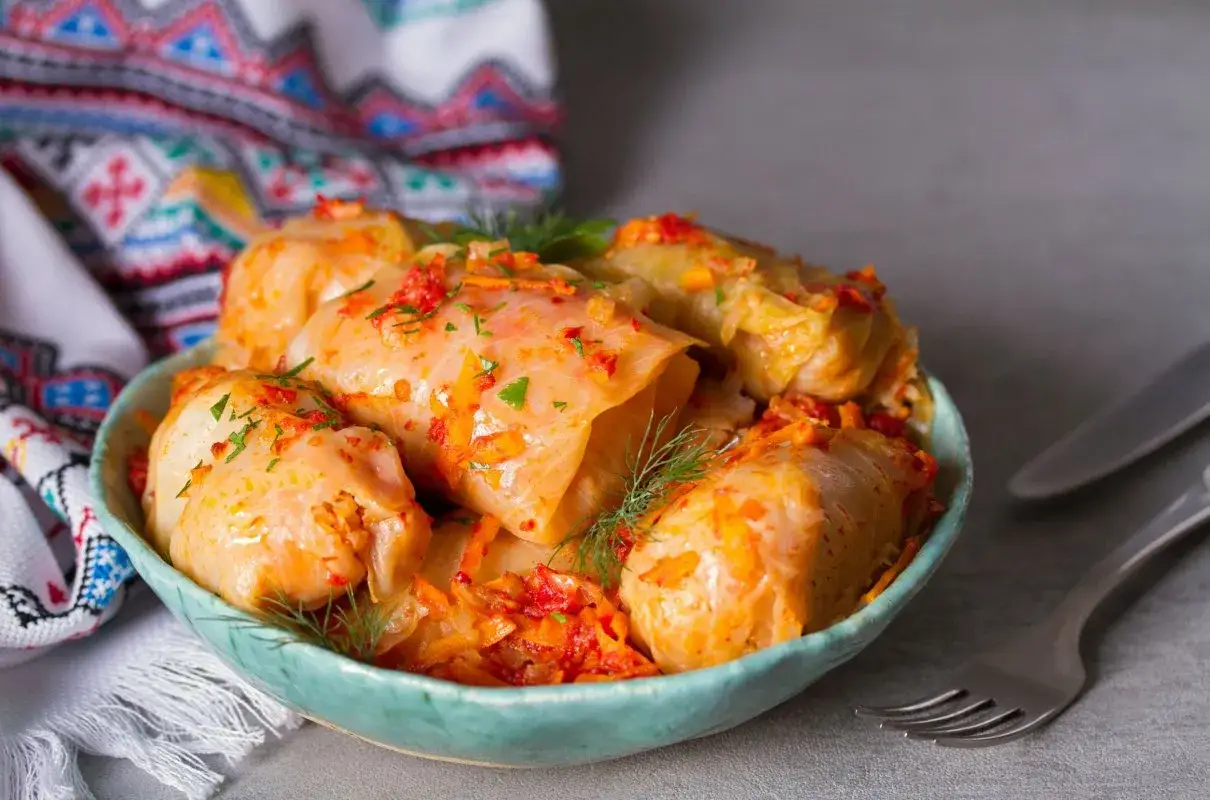 Pyszne gołąbki w sosie pomidorowym, podane w misce. Zastanawiasz się, czemu gołąbki nazywają się gołąbki? Może przez ich kształt, przypominający ptaka?