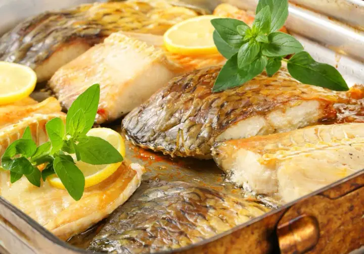 Chrupiący karp z piekarnika, podany z cytryną i ziołami, kusi apetycznym wyglądem.